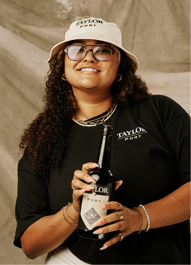 Woman wearing Taylor Port merch posting with bottle